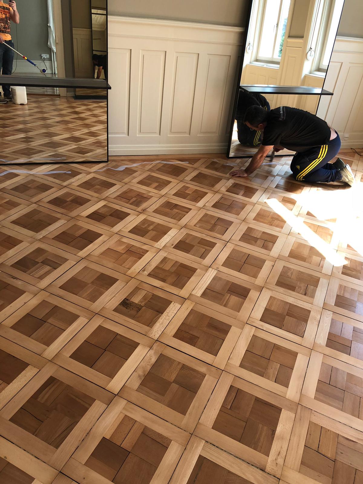 Parkettleger bei der Arbeit auf einem Mosaikparkett