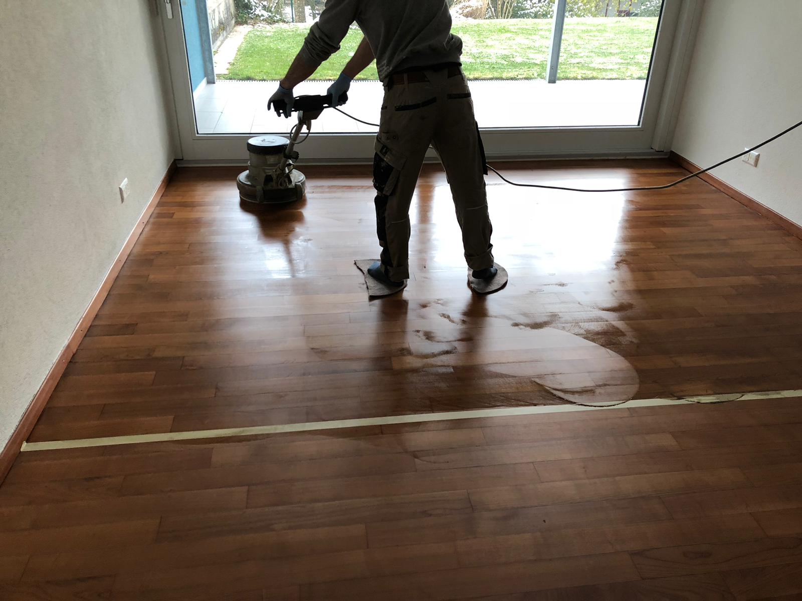 Fachmann schleift einen Holzboden in einem Raum mit grossem Fenster